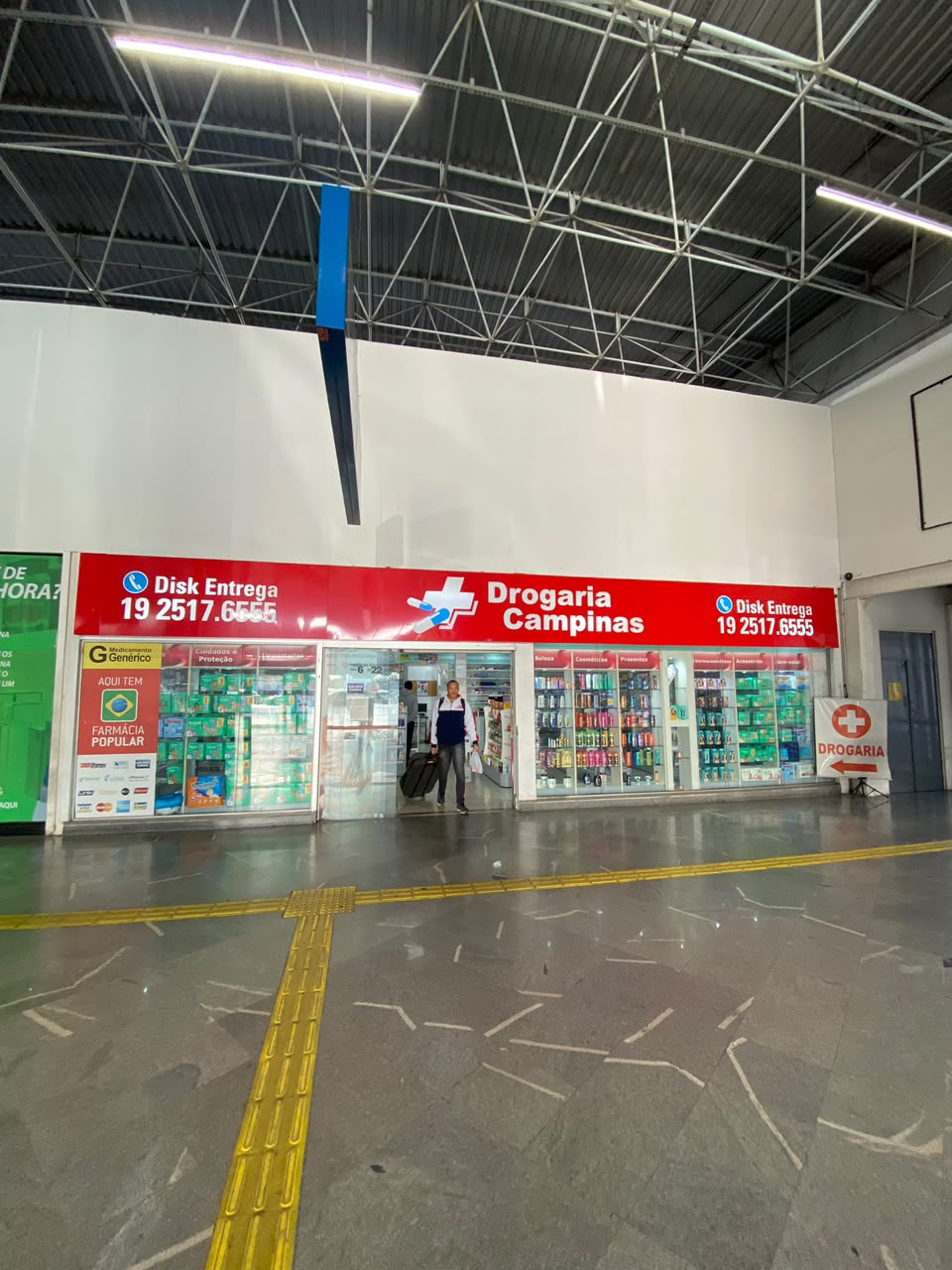 Fachada da Drogaria Campinas dentro da Rodoviária de Campinas, com placa vermelha de disk entrega