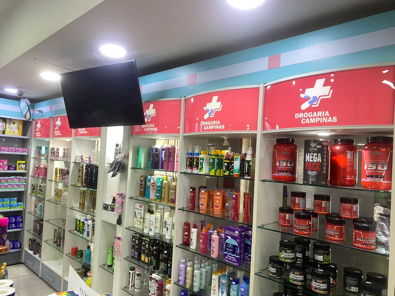 Prateleira com potes de whey protein, glutamina e creatina na Drogaria Campinas